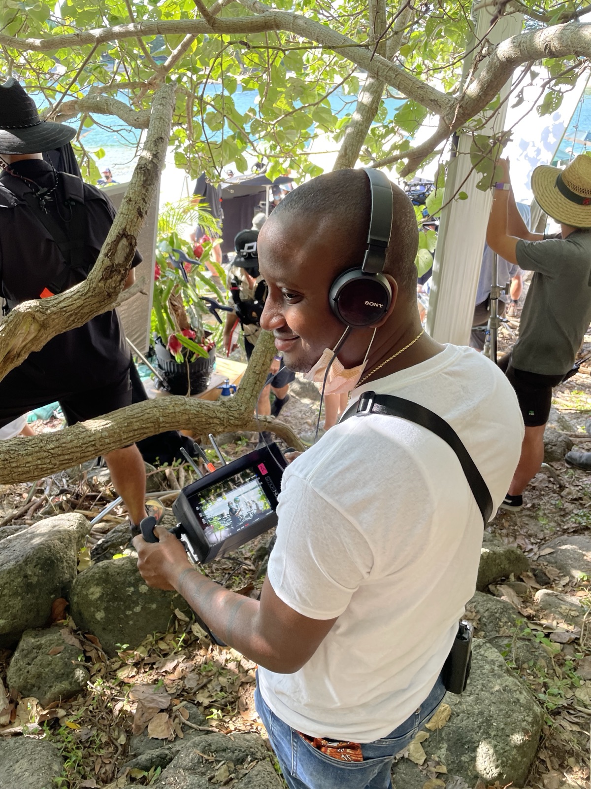 KaMeek on a film set, wearing headphones and holding a production monitor